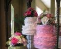 Three sets of two tiered cakes atop different sized stands. All cakes are covered in white, pink and green buttercream and fondant. Flowers in different soft tones add a fresh look to this wedding cake setup. Beautiful, chic and girly! 